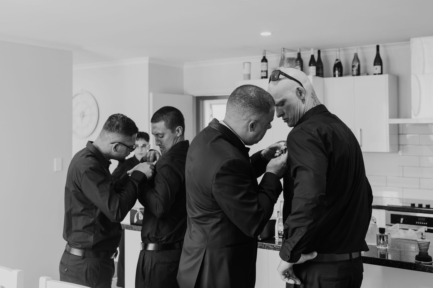 A black and white photo series showing a group of men in suits hugging and embracing each other emotionally.