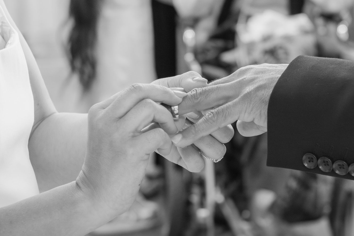 A close-up black and white photo of wedding guests toasting with champagne glasses.