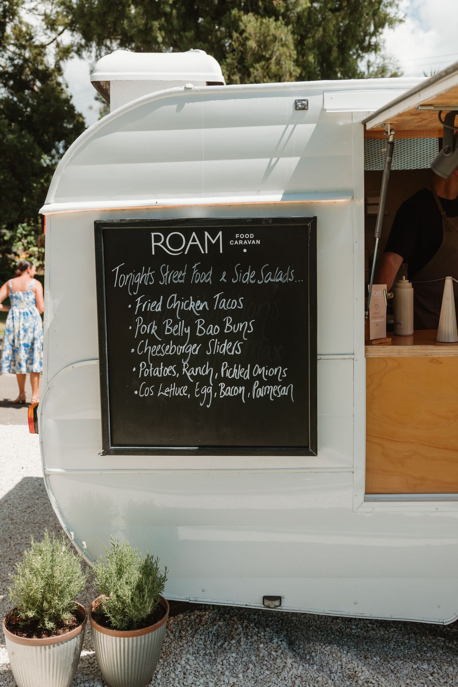 Roam Food Caravan truck with chalkboard menu featuring fried chicken tacos, pork belly bao buns, and cheeseburger sliders.