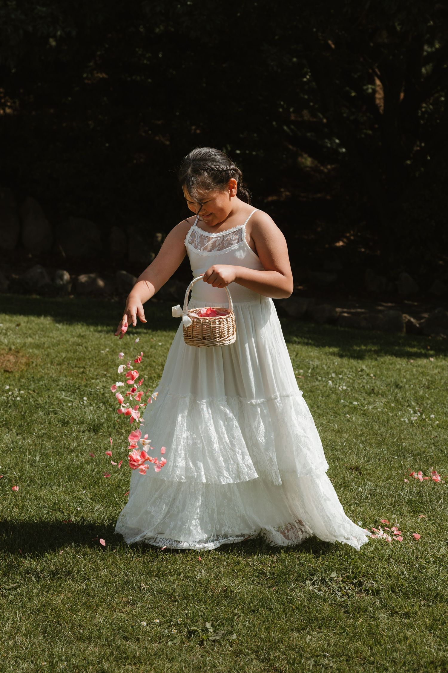 A series of photos showing someone in a white dress scattering flower petals on a sunny lawn.