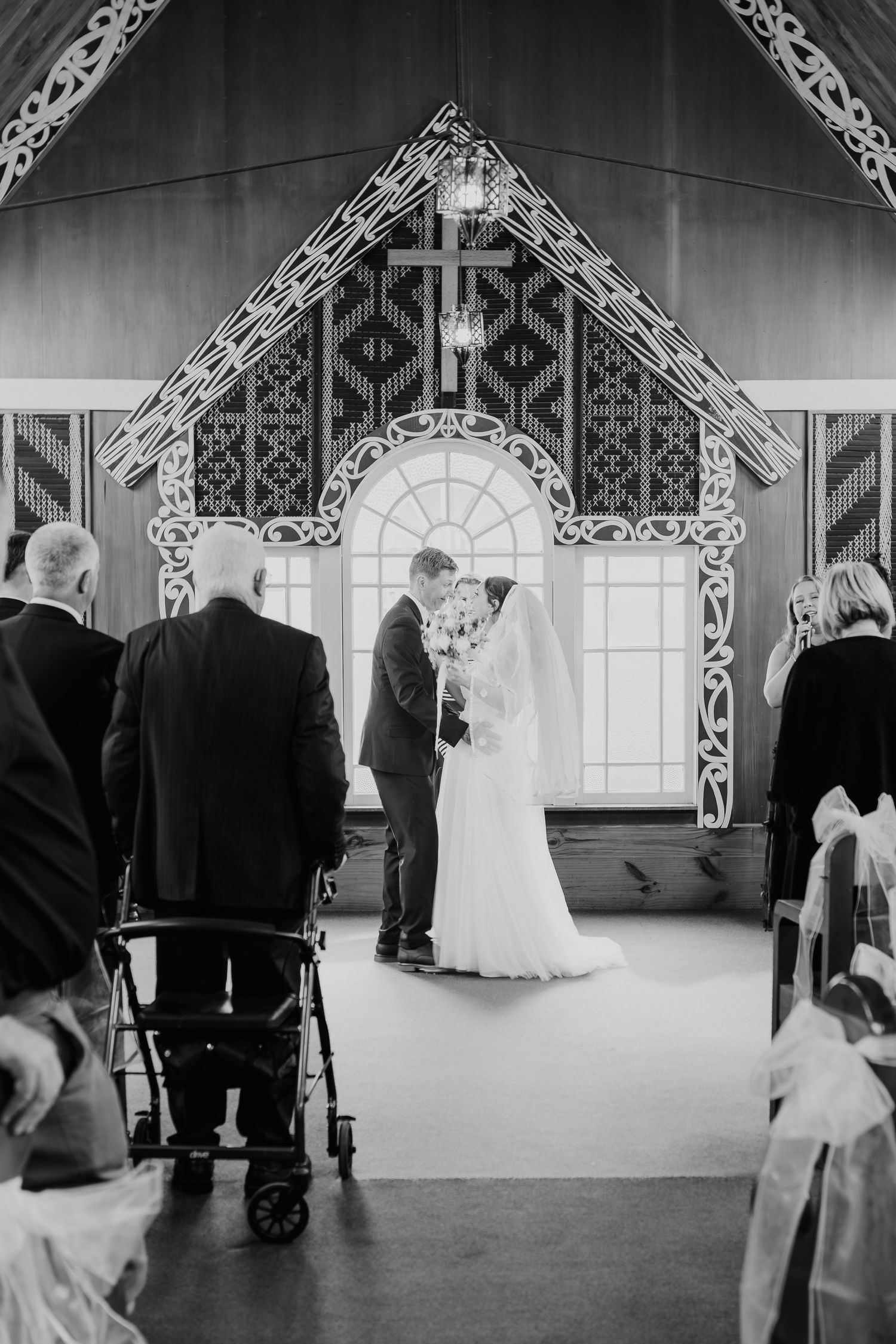 Wedding ceremony in progress under an ornate architectural arch with intricate white details.