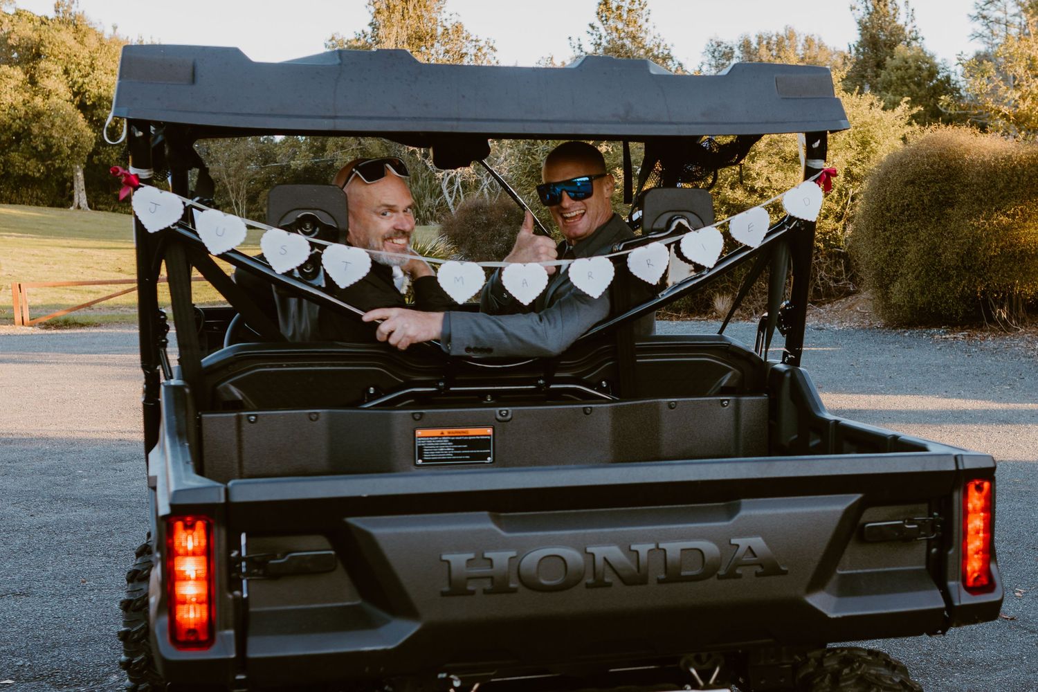 A black Honda utility vehicle decorated with heart garlands parked outdoors during golden hour.