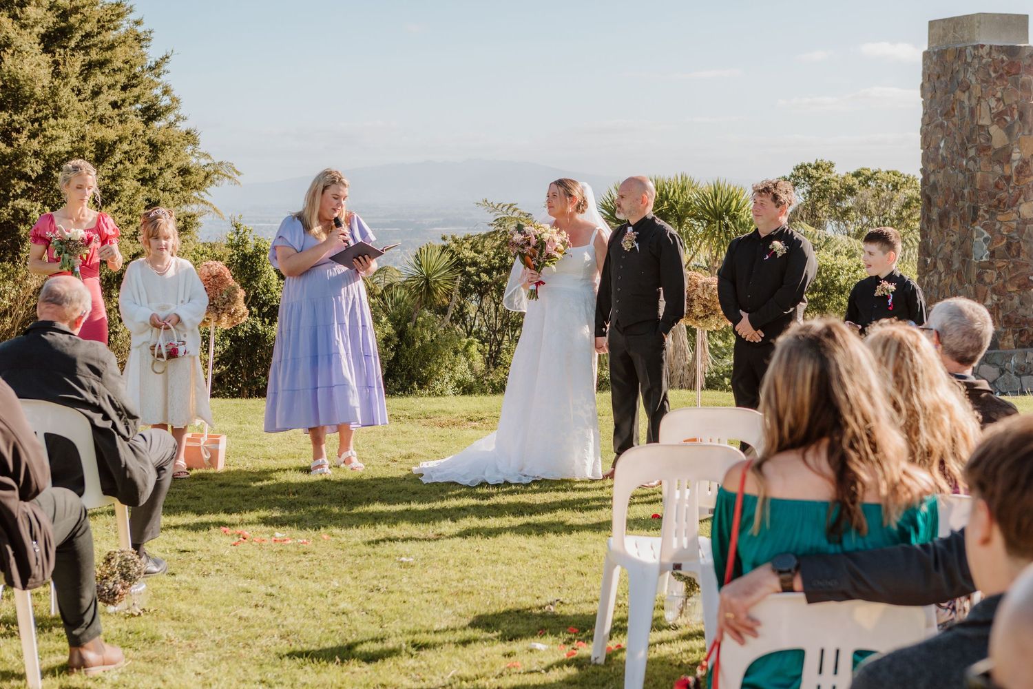 Beautiful hilltop outdoor wedding ceremony with scenic mountain views in the background and guests gathered on the lawn.