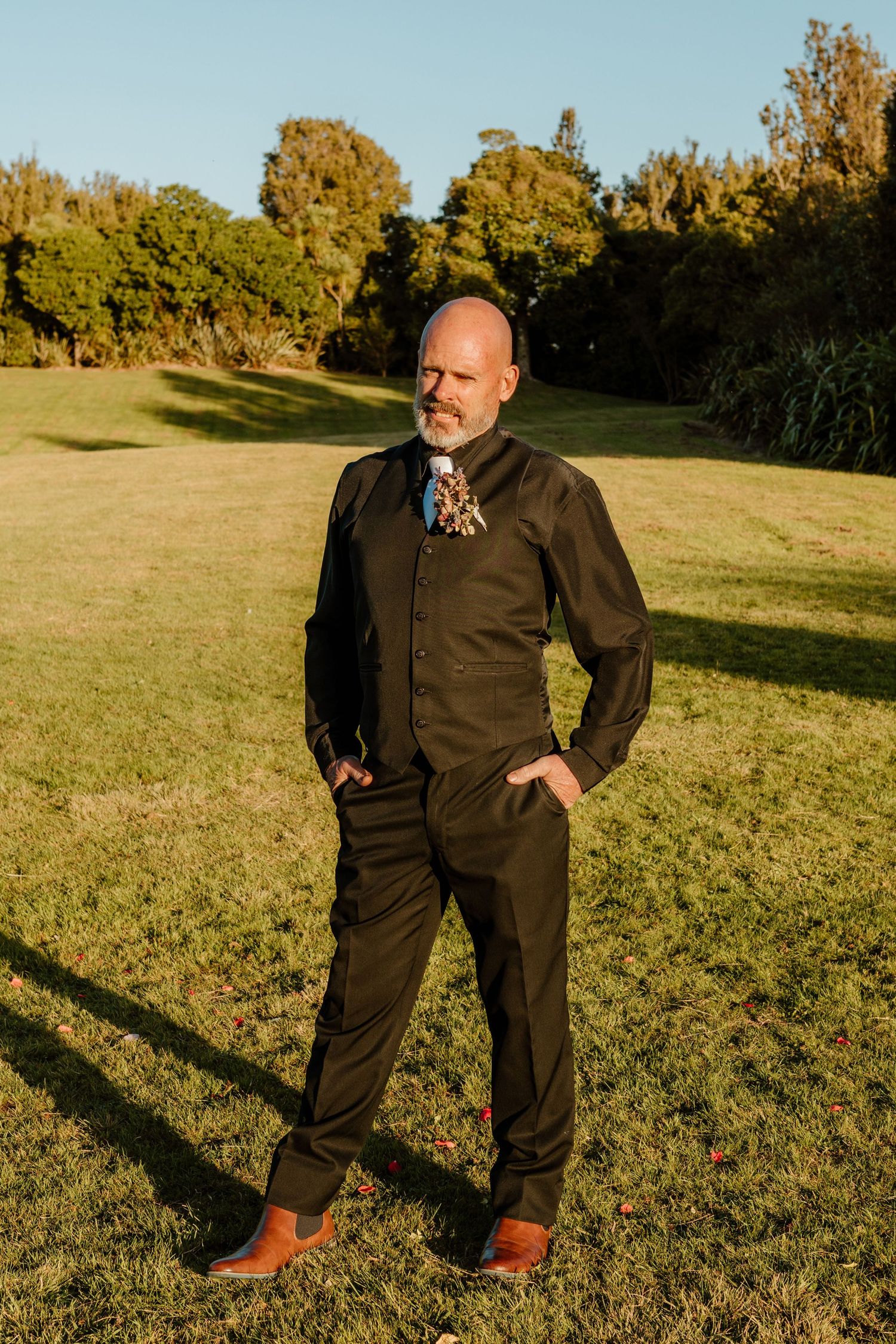 A person wearing dark clothing stands in a sunny grassy field during golden hour.