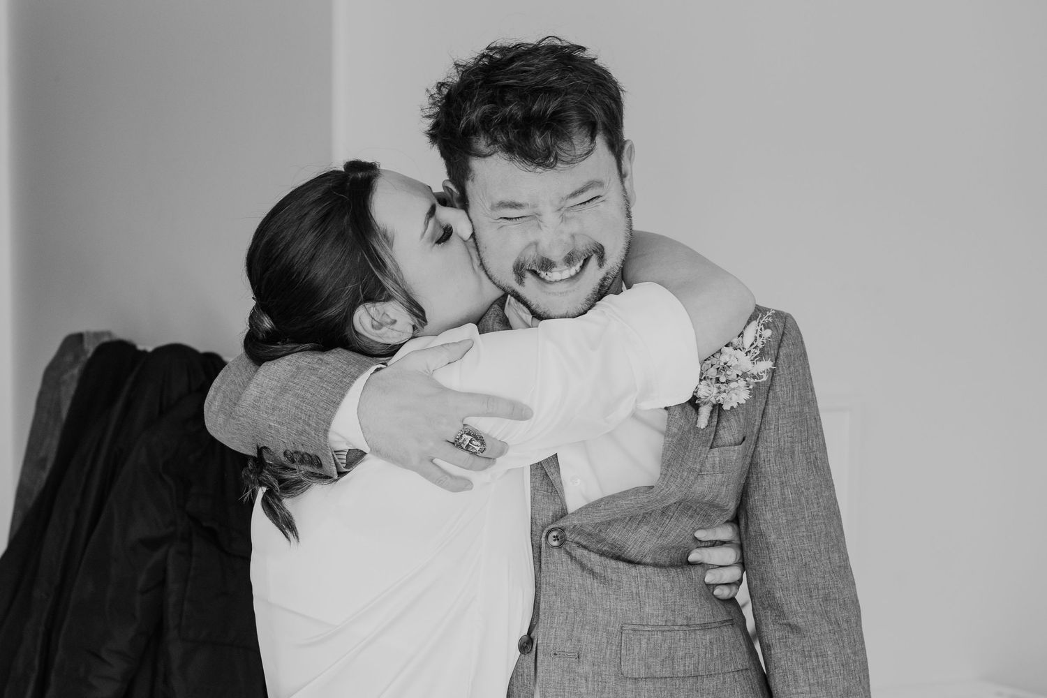 A laughing couple embraces in a candid black and white photo showing genuine joy and connection.