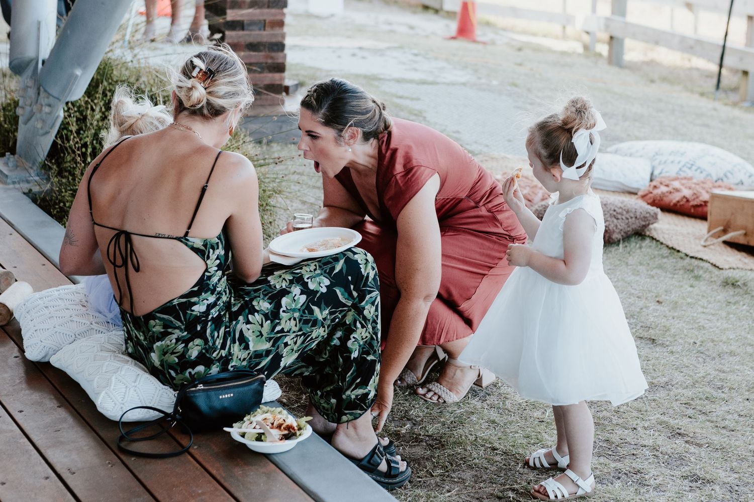 Wedding attendees relaxing on the grass during an outdoor reception. Papamoa Surf Lifesaving Club Wedding