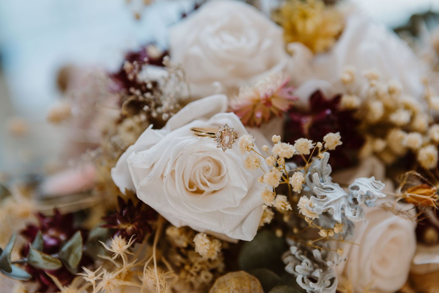 Delicate floral arrangement featuring soft white roses and dried flowers in muted tones.