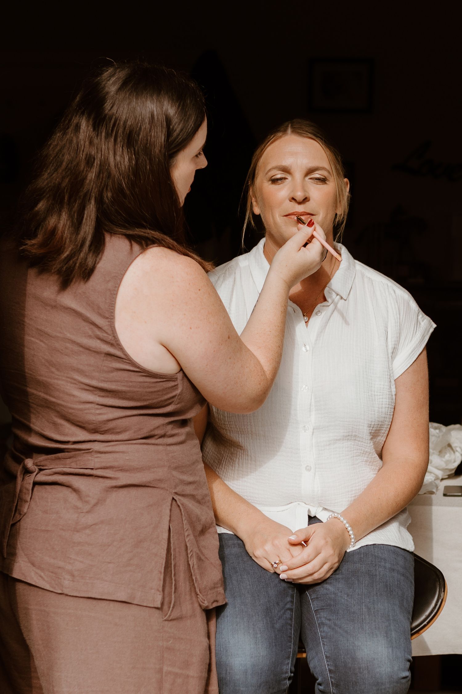 A heartfelt sequence shows two people sitting together as one applies makeup to the other in a tender moment.