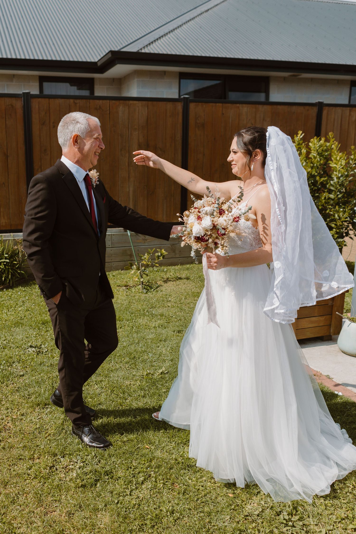 Emotional first look between bride and older guest in backyard garden setting.