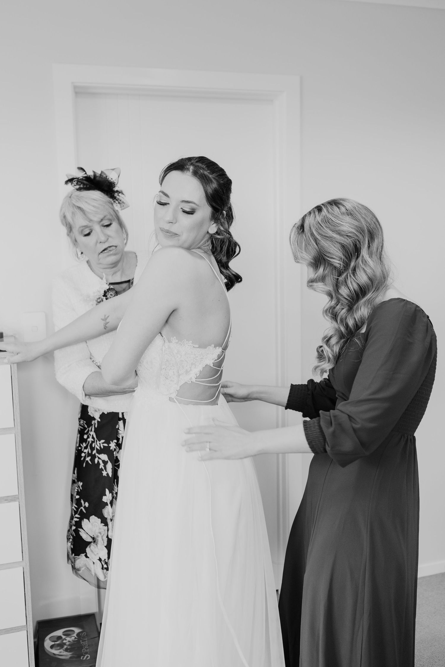 Wedding preparation scene showing dress adjustments in monochrome.