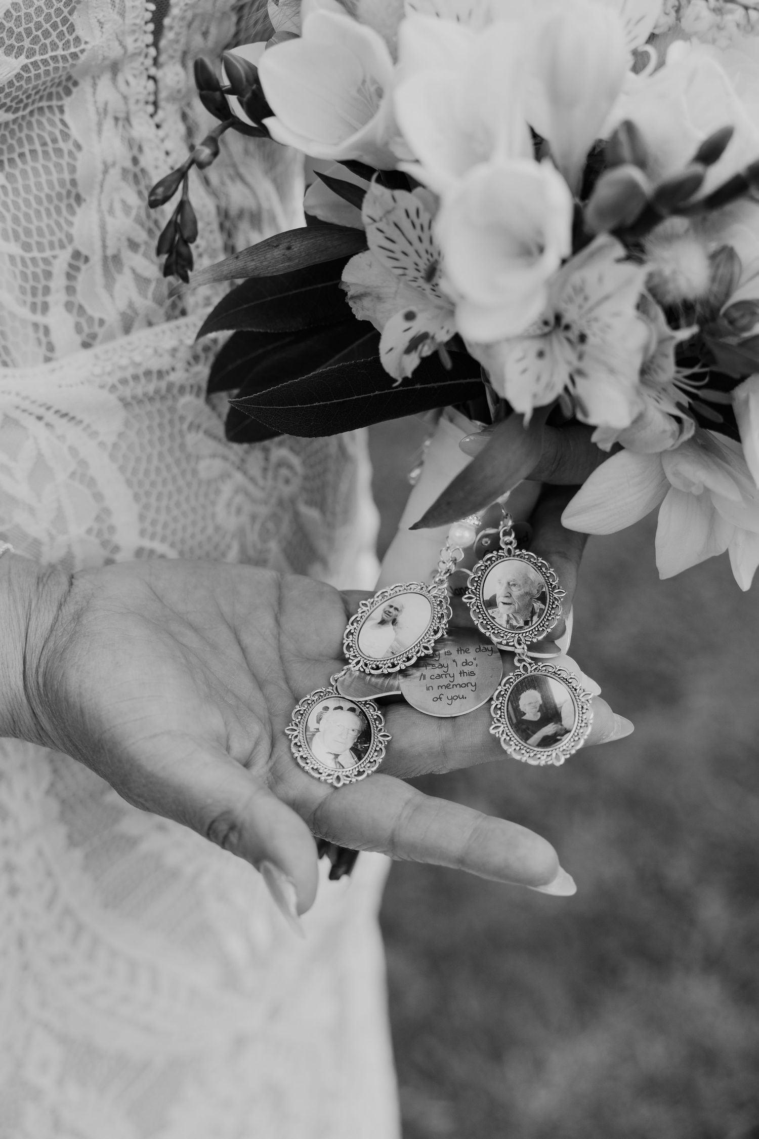 Black and white photograph showing hands holding vintage cameo jewelry with delicate floral arrangements in soft focus.