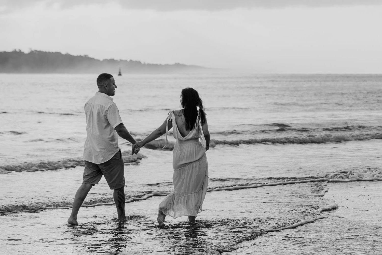 A couple walks together along a scenic beach at sunset while holding hands and enjoying the ocean view.