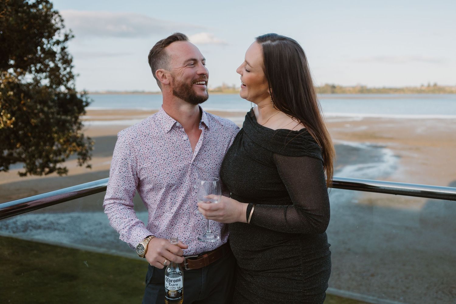 Couple shares romantic moments at sunset along a coastal pathway in matching outfits.