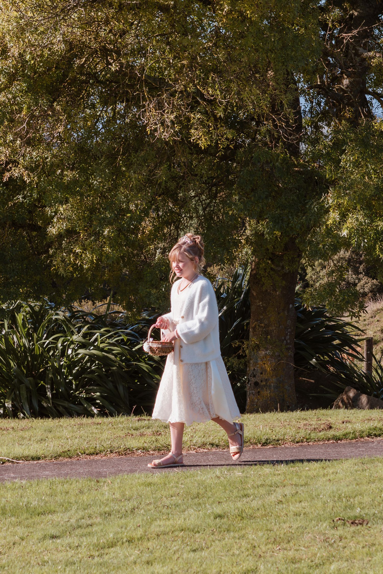 A series of photos showing someone in a white dress crouching and squatting down on a grassy hill under trees.