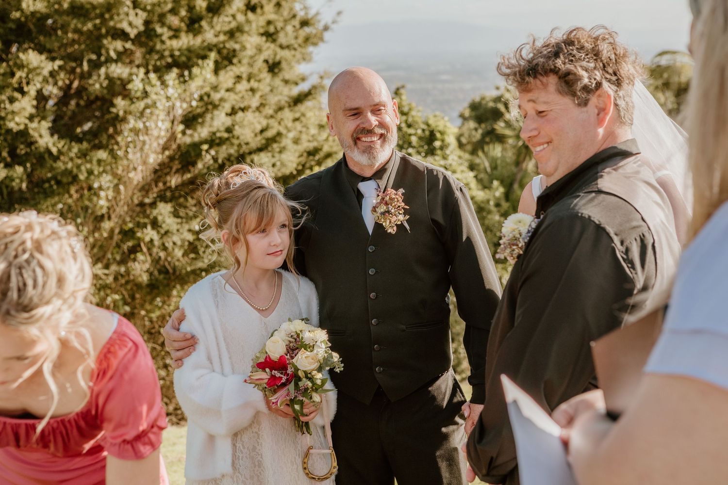 Multiple wedding photos showing intimate moments during a sunny outdoor ceremony with guests watching.