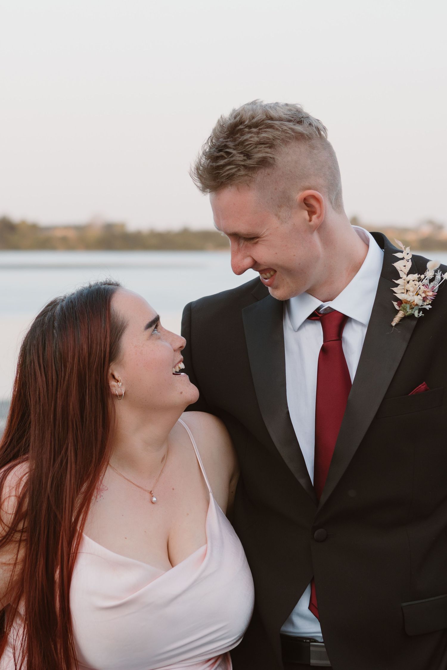 Romantic moment between bride and groom sharing loving glance at waterfront wedding.