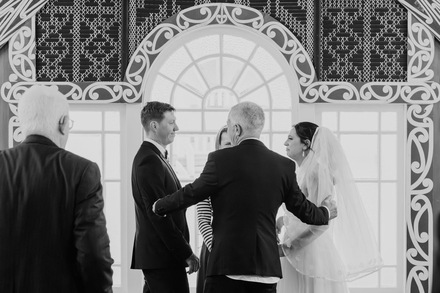 Black and white photo of a wedding ceremony moment under decorative architectural elements.