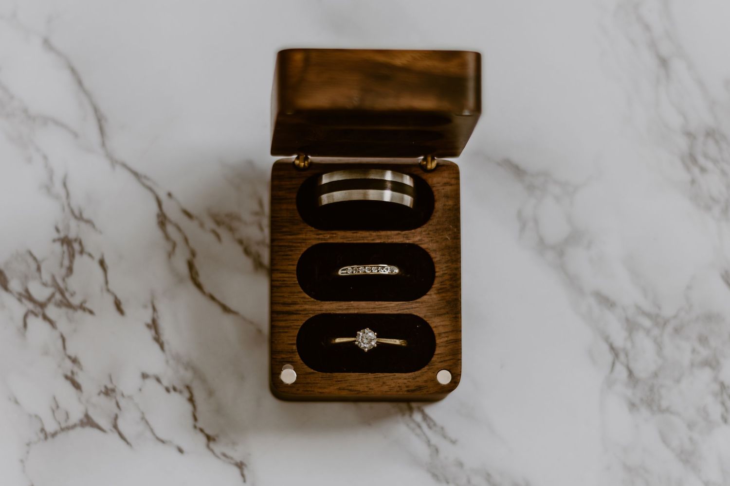 Three wooden music boxes with gold embellishments sit on a white marble surface.
