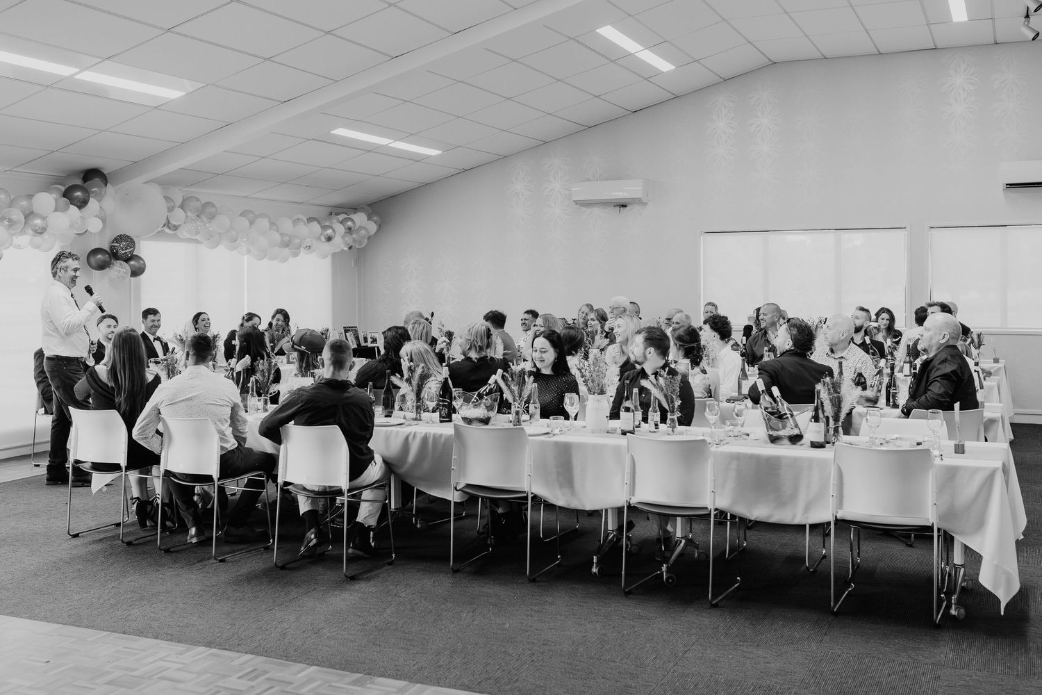 Wedding reception hall set with multiple round tables and white linens.