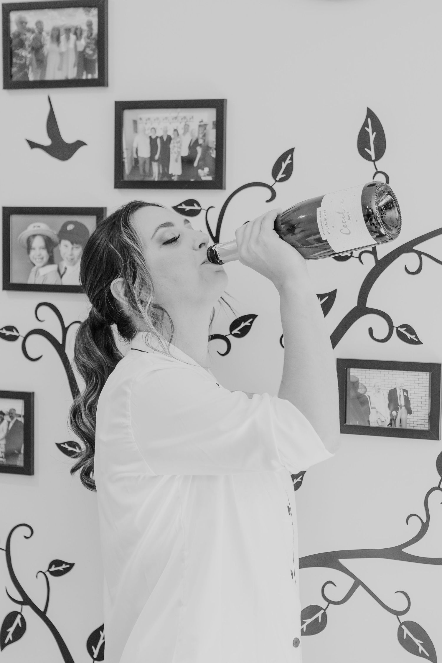 Black and white image showing getting ready moments against a wall with decorative vine decals.