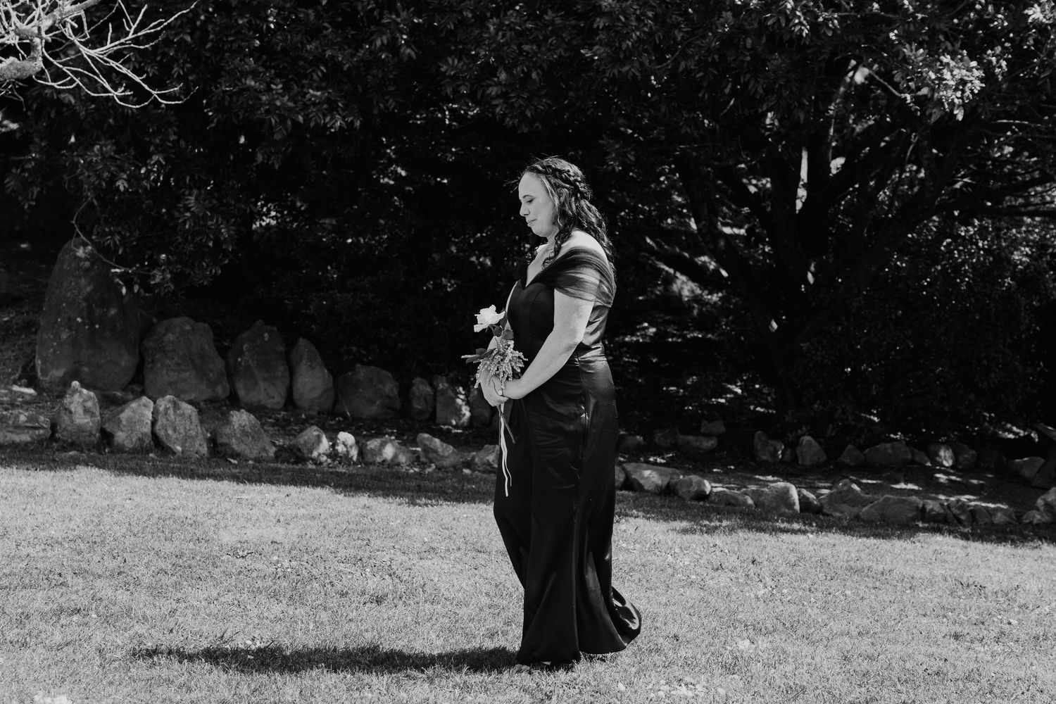 A sequence of black and white photos showing a couple in formal attire walking together on grass during an outdoor event.