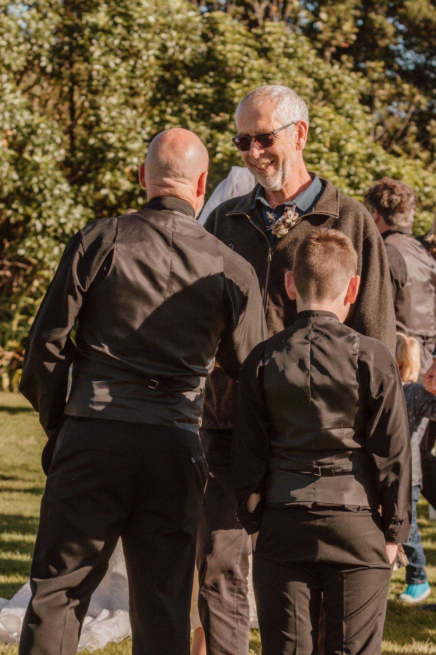 Seven sequential photos show people in black attire sharing a touching embrace outdoors in a sunlit garden.