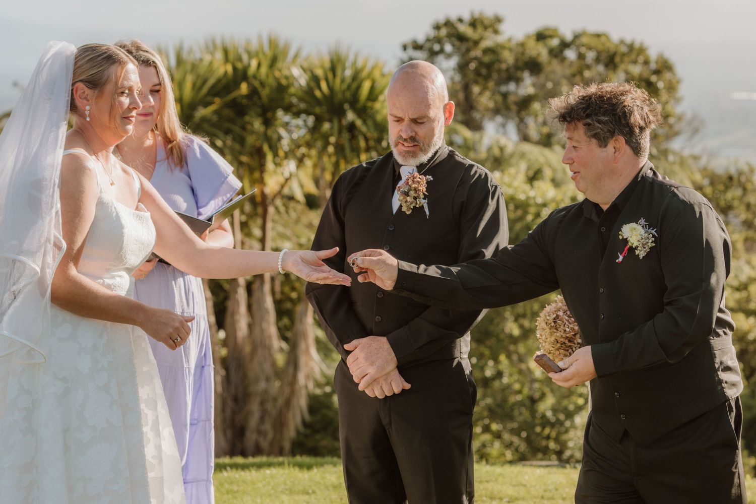 Hands join together in prayer during an emotional outdoor wedding ceremony with palm trees in the background.