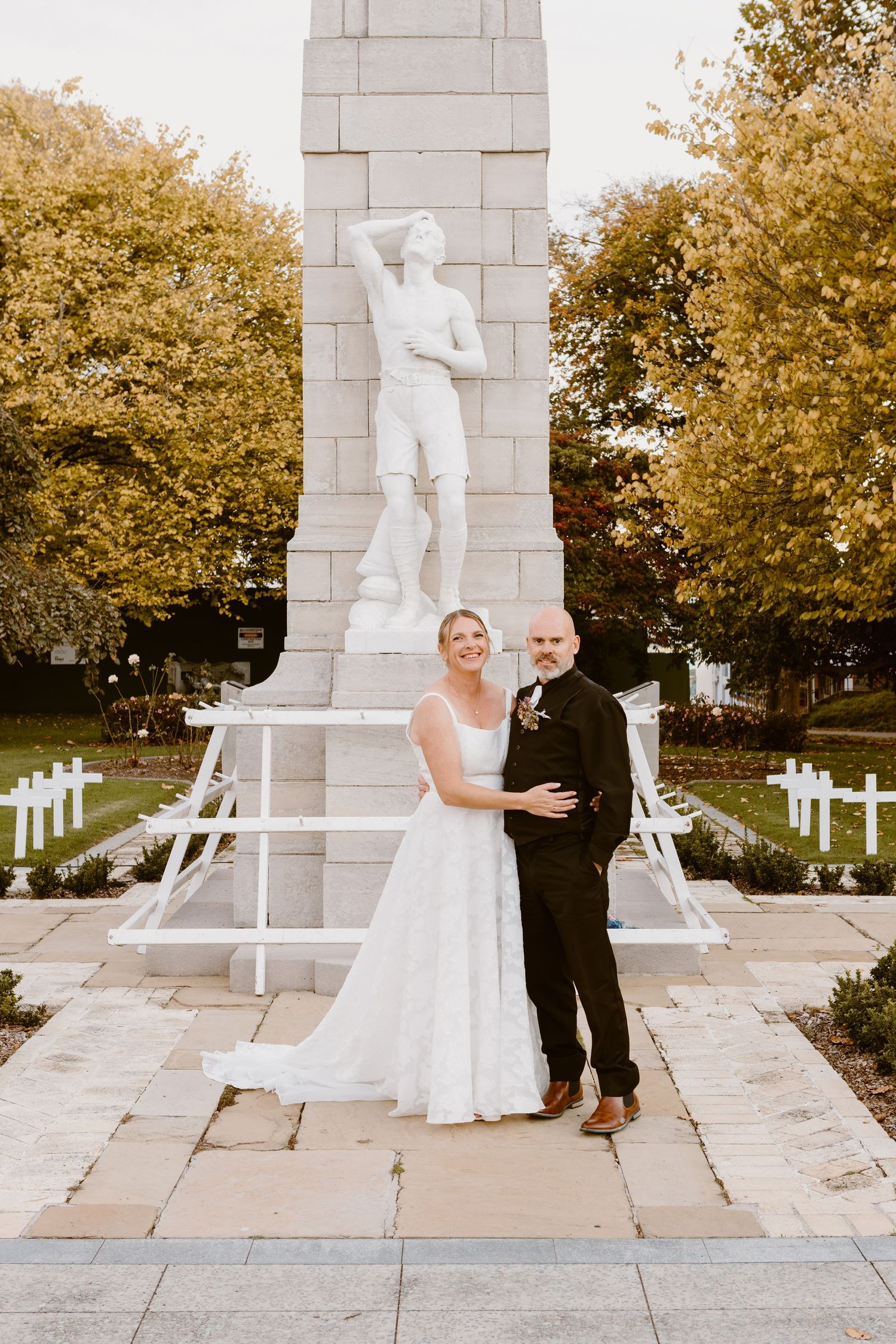 Romantic wedding couple portrait sequence showing progression of poses at stone monument in autumn garden.