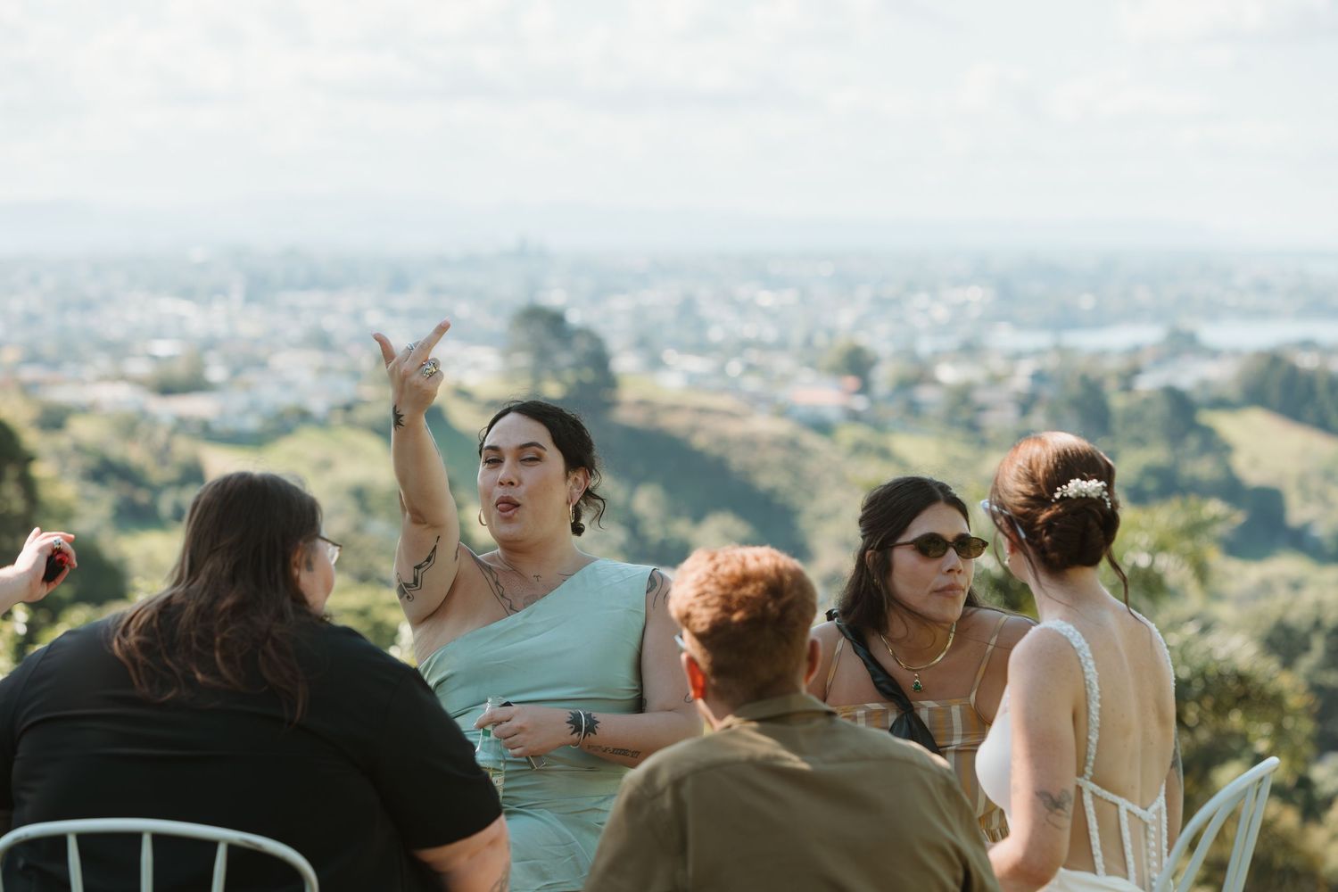 Group of women socializing outdoors at a hilltop venue with panoramic city views in the background.