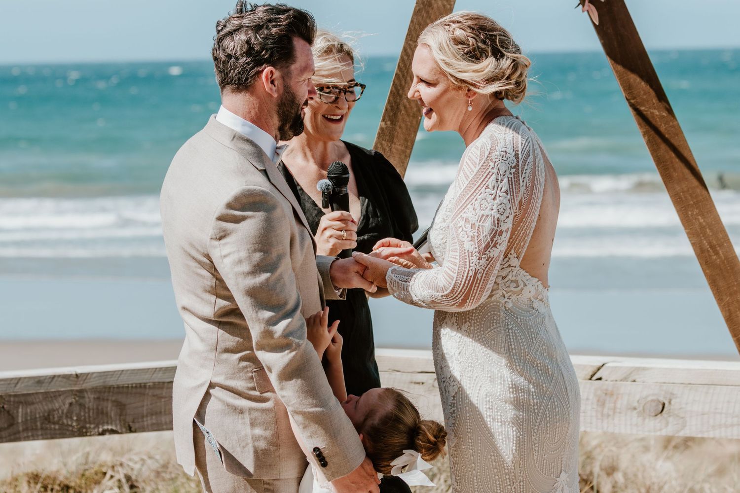 A beachside wedding ceremony with waves crashing in the background. Papamoa Surf Lifesaving Club Wedding