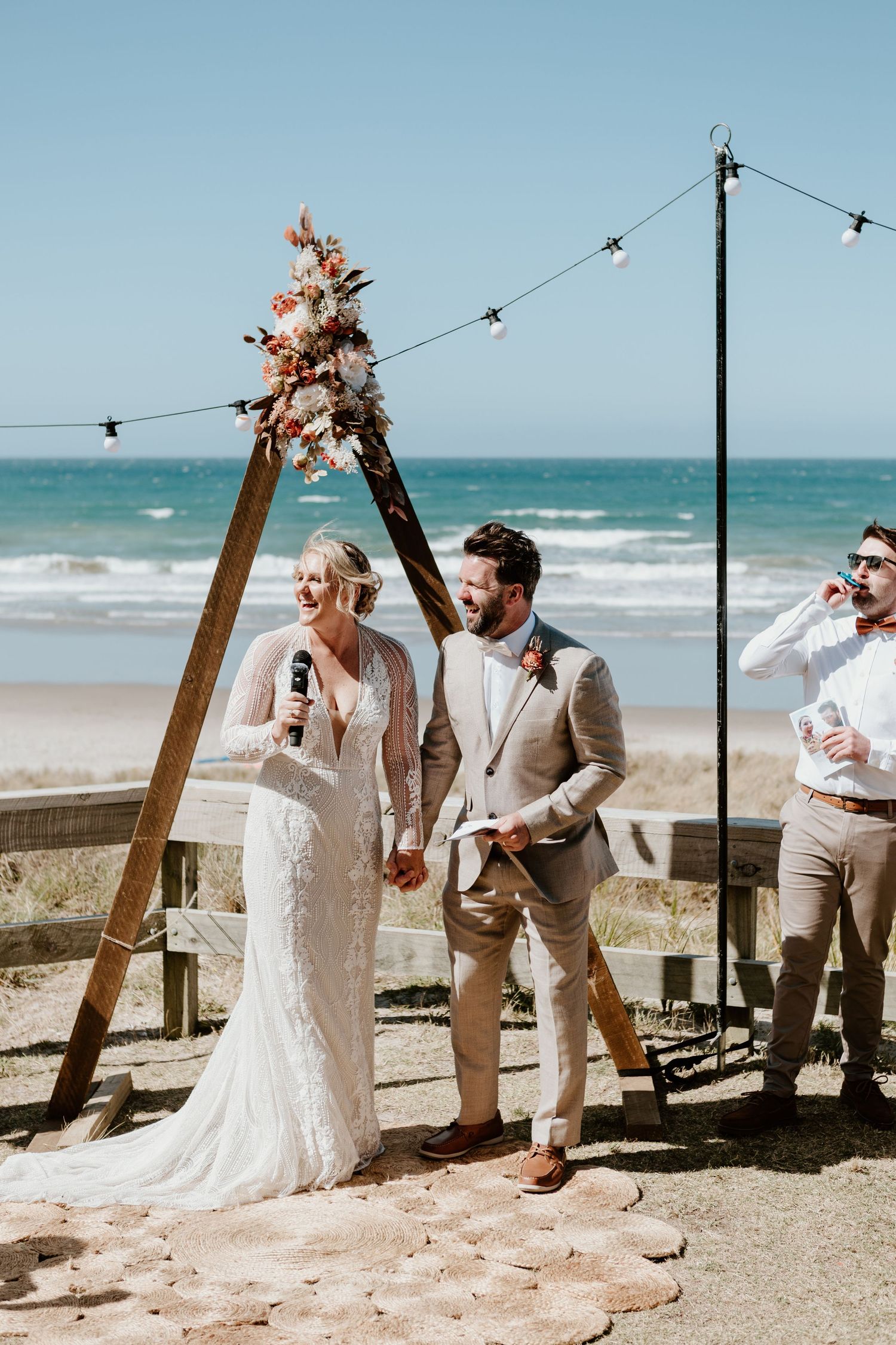 A joyful beach wedding celebration with string lights and ocean views. Papamoa Surf Lifesaving Club Wedding
