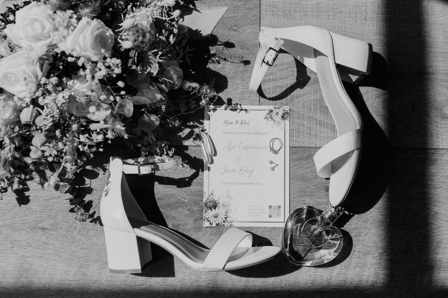 Wedding day details including bouquets, shoes and accessories arranged in black and white.