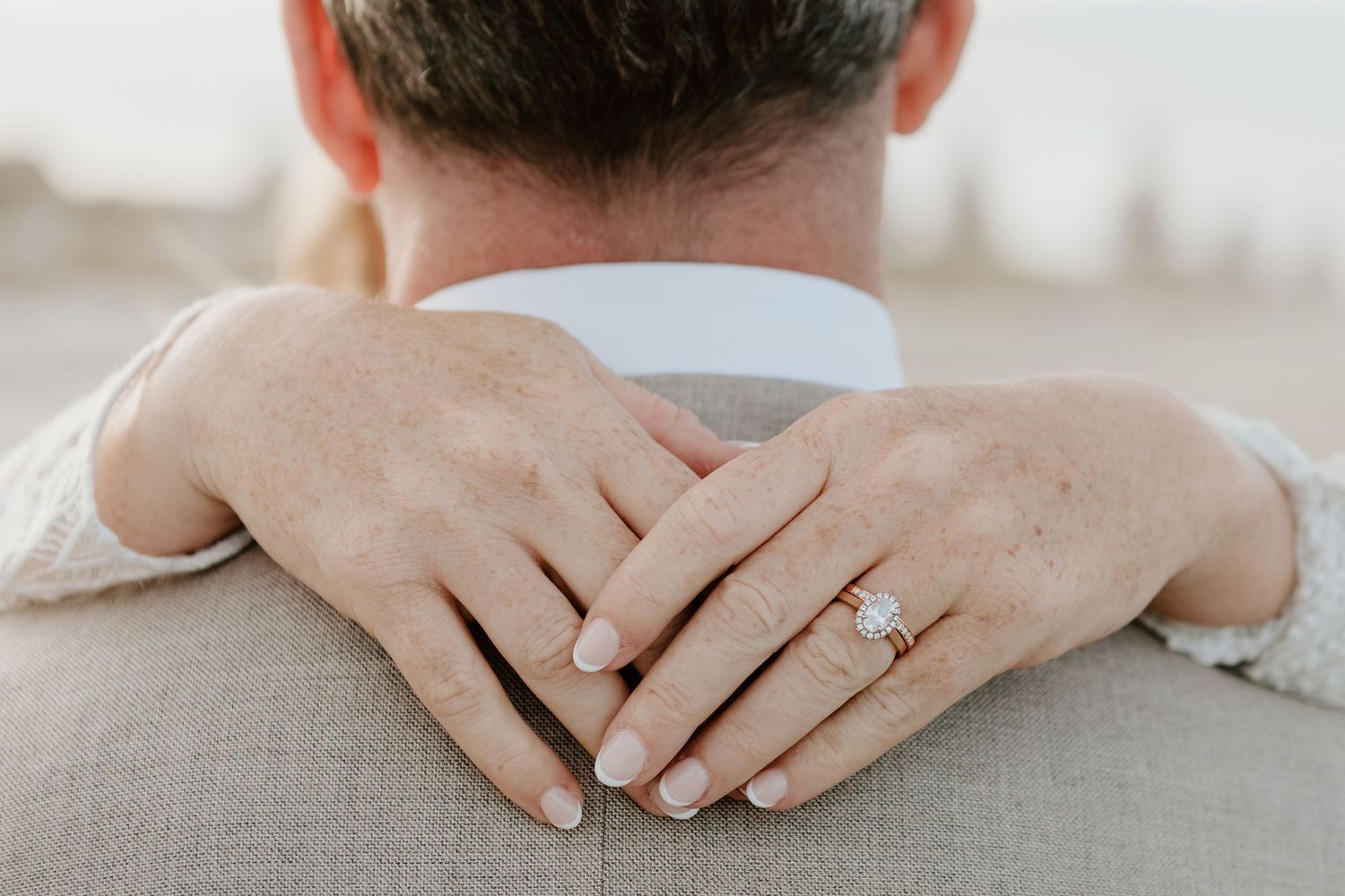 Wedding rings displayed on hands resting on a white surface. Papamoa Surf Lifesaving Club Wedding