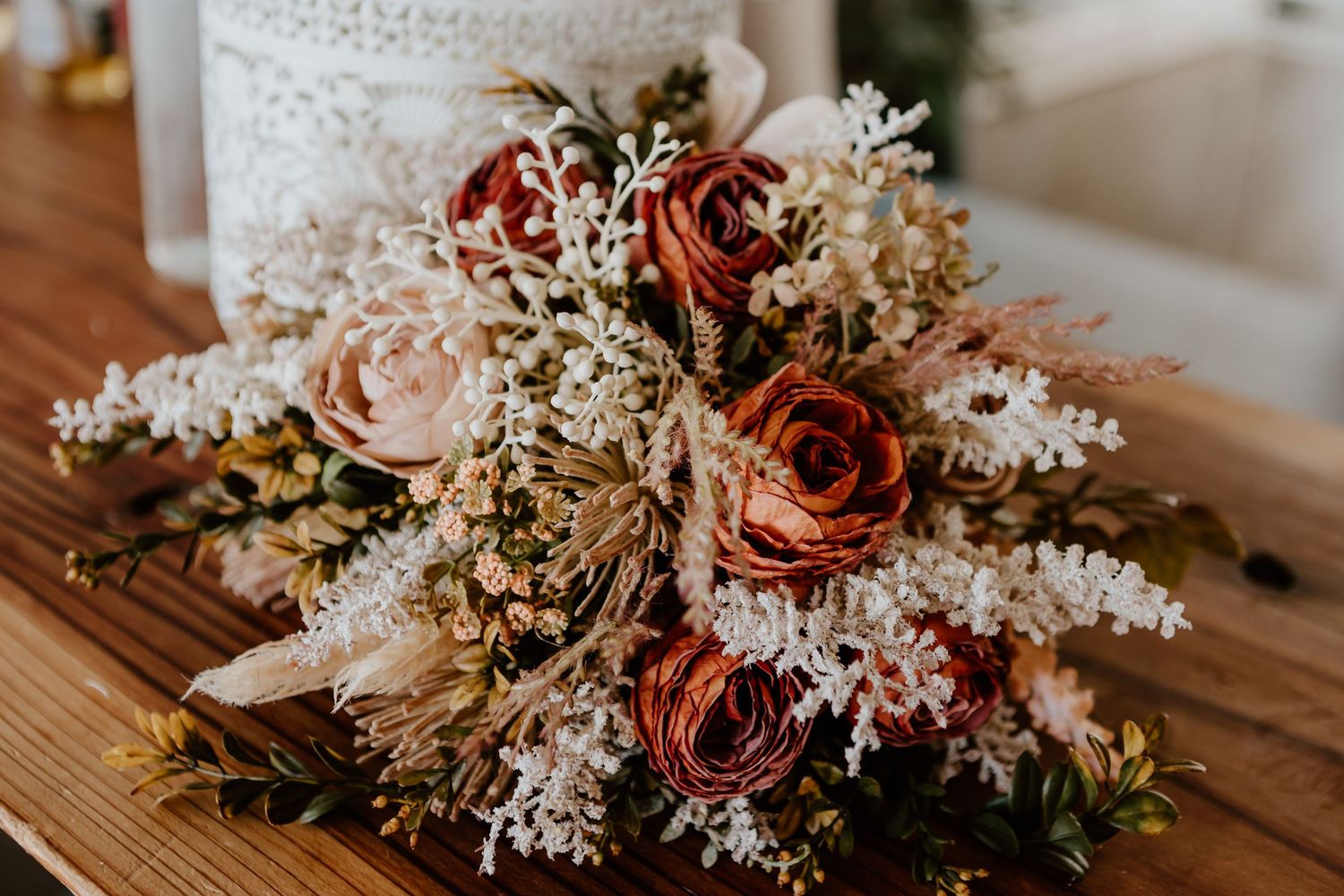 A romantic floral arrangement with mauve roses and delicate white flowers displayed on a wooden surface.