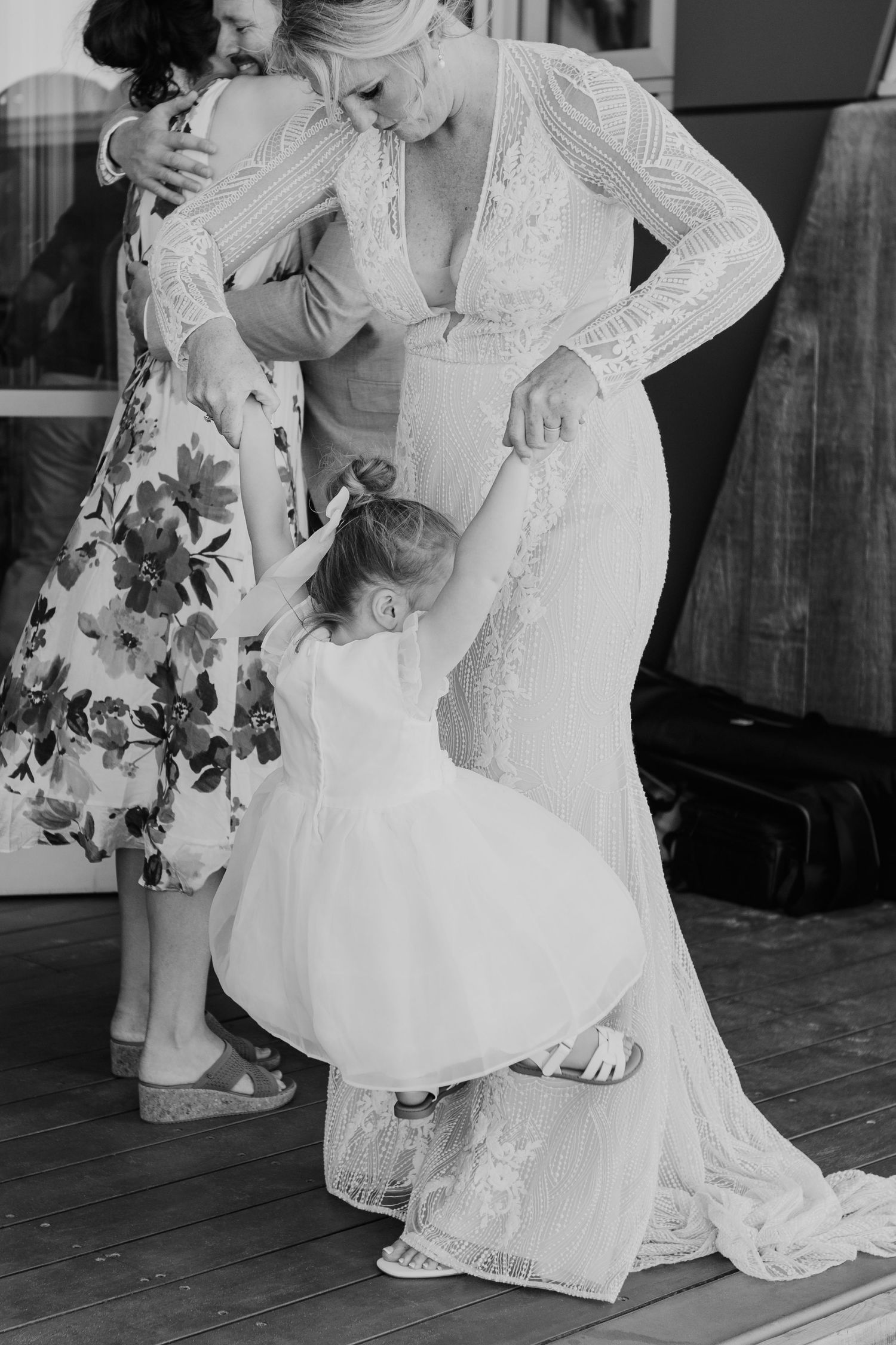 A touching moment between a bride in a lace gown and a small child in white during a wedding celebration. Papamoa Surf Lifesaving Club