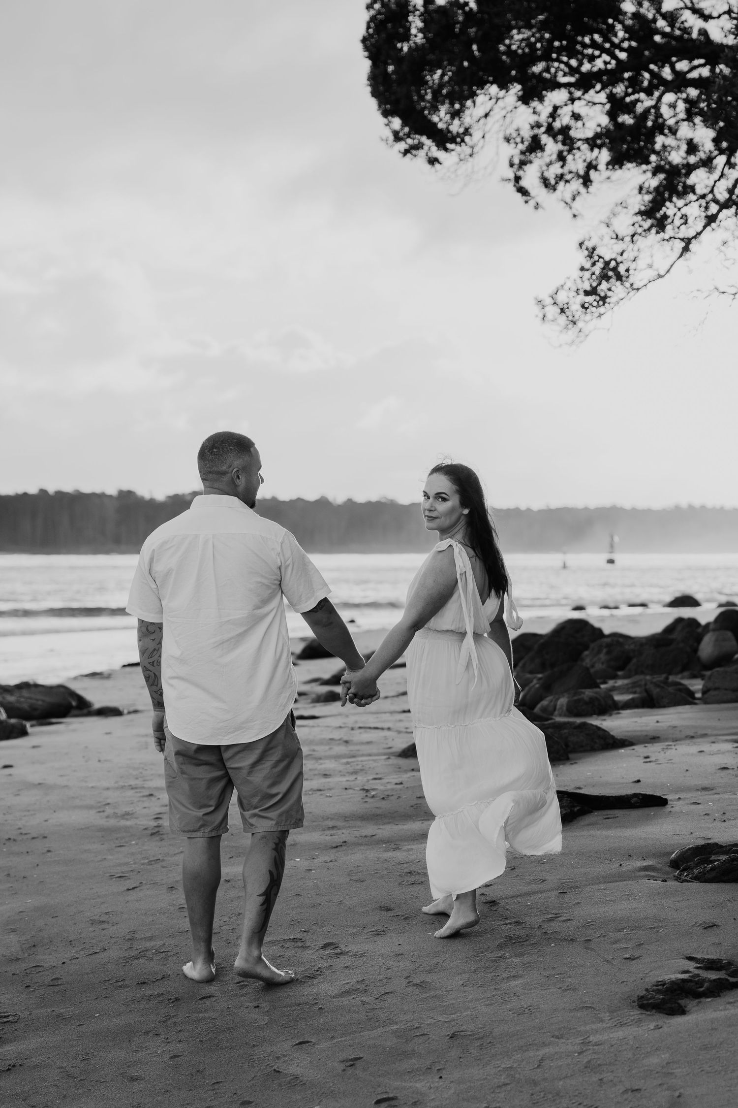 A couple walking hand in hand along a rocky beach at sunset, captured in a series of black and white photos.