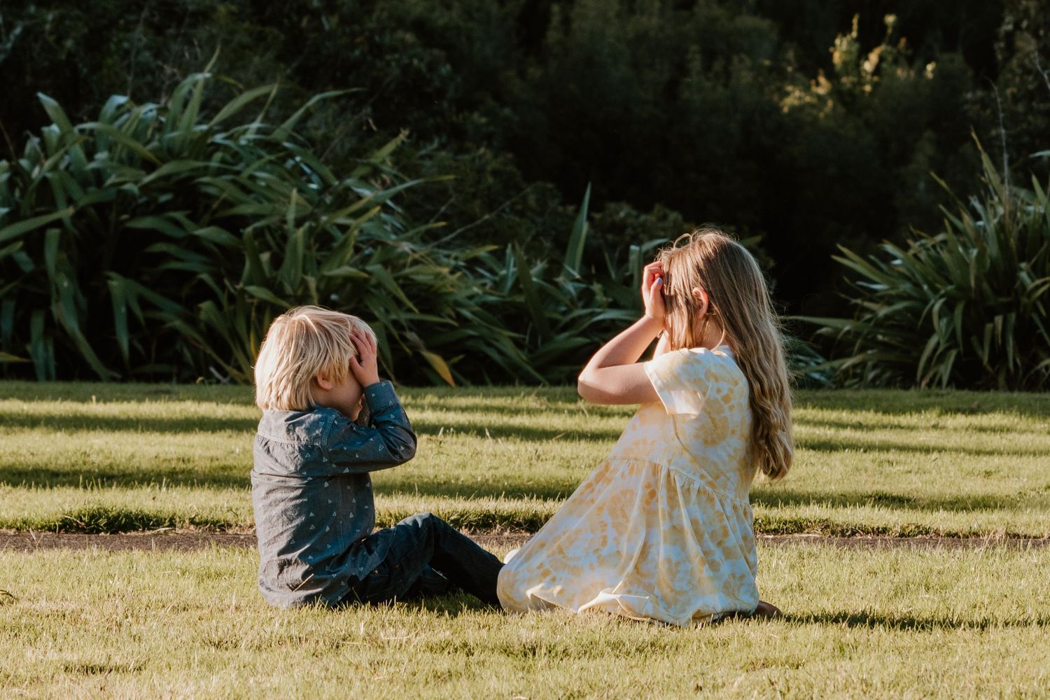 A group of people relax on a sunny lawn while sitting in comfortable poses during a summer afternoon.