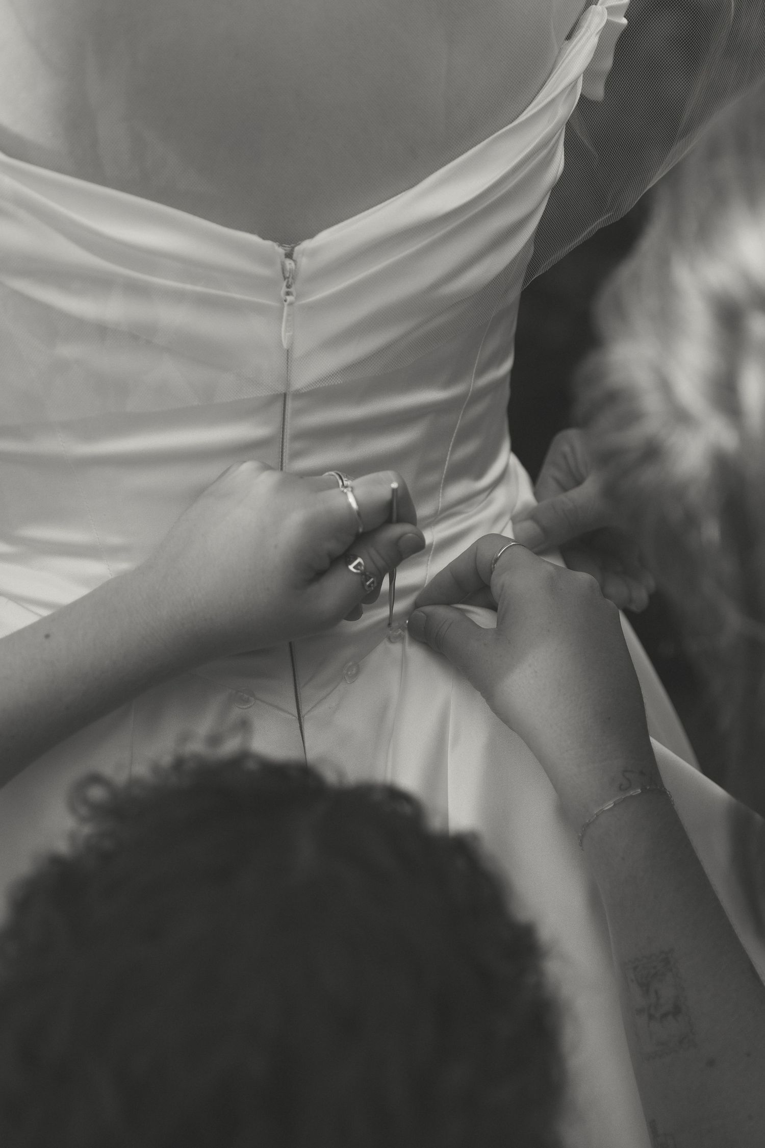 Detail shot of a white wedding dress being adjusted.