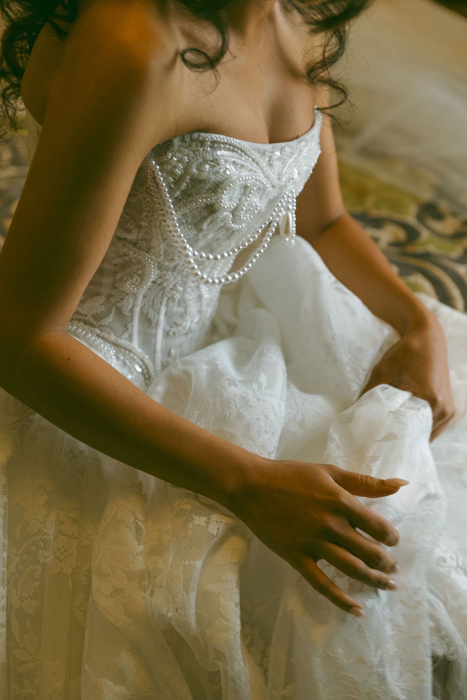 Bride showing the lace details of her wedding dress, photographed by a Southern California wedding photographer
