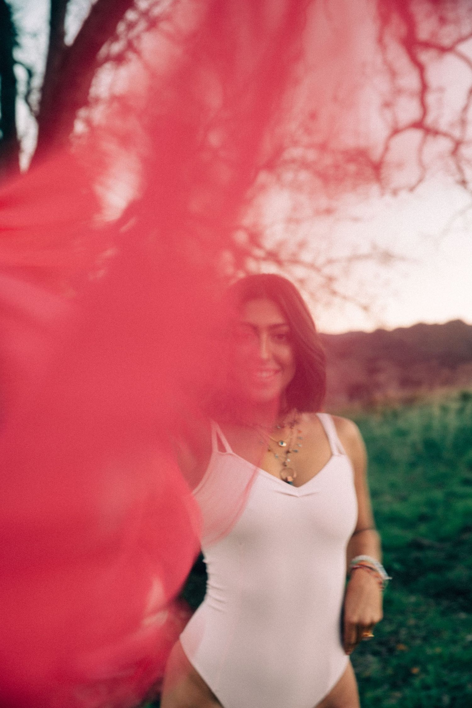 Red light leak effect creates dreamy atmosphere around figure in white top.