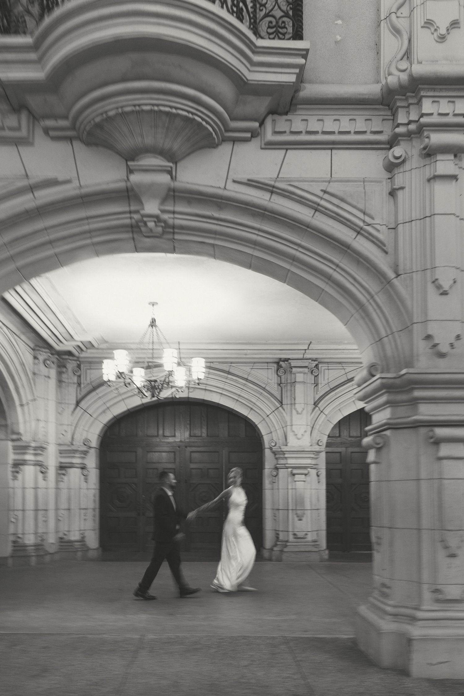 Black and white sequence of a couple dancing in a grand ballroom with ornate architecture.