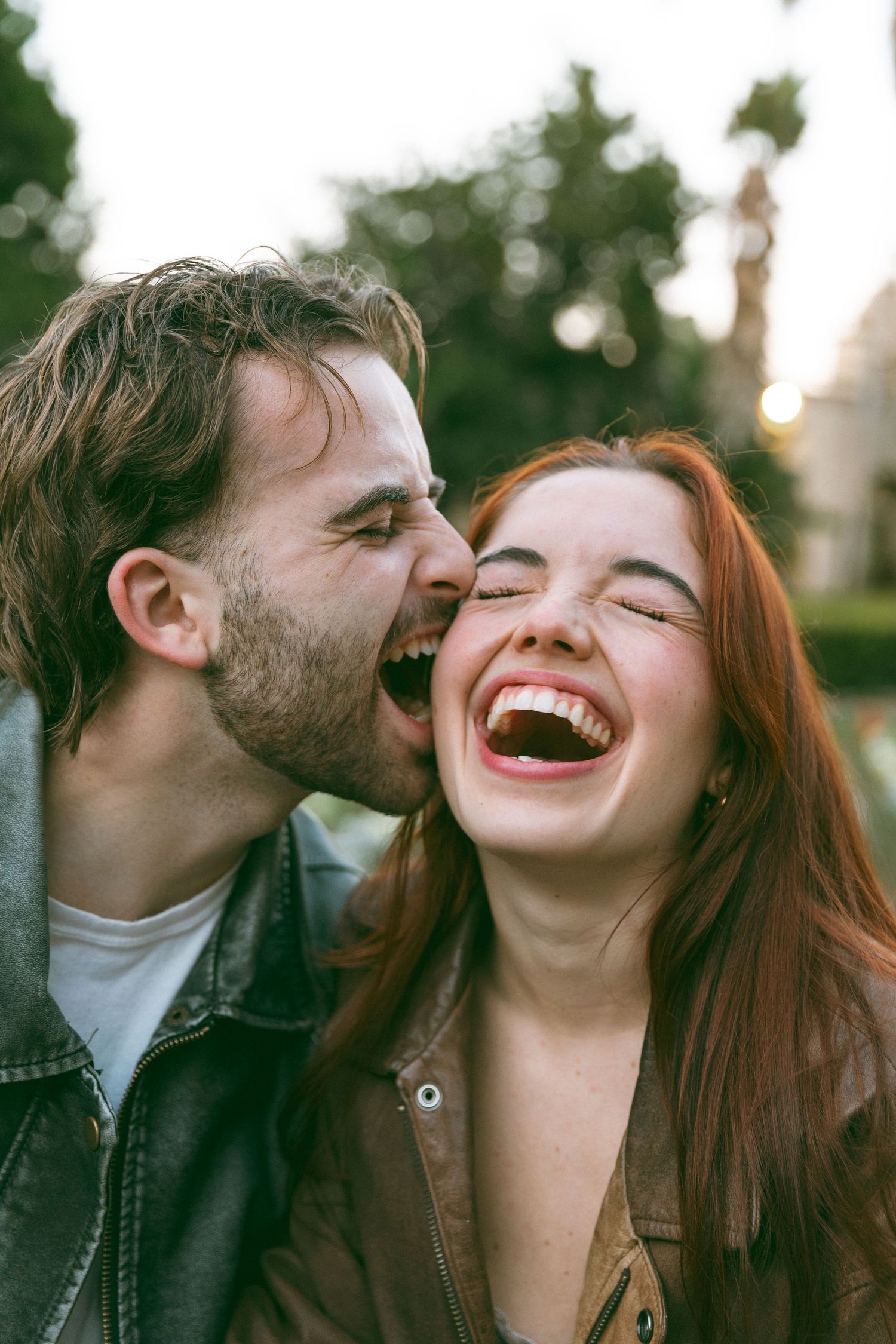 Joyful laughter and affection captured in candid outdoor portrait.