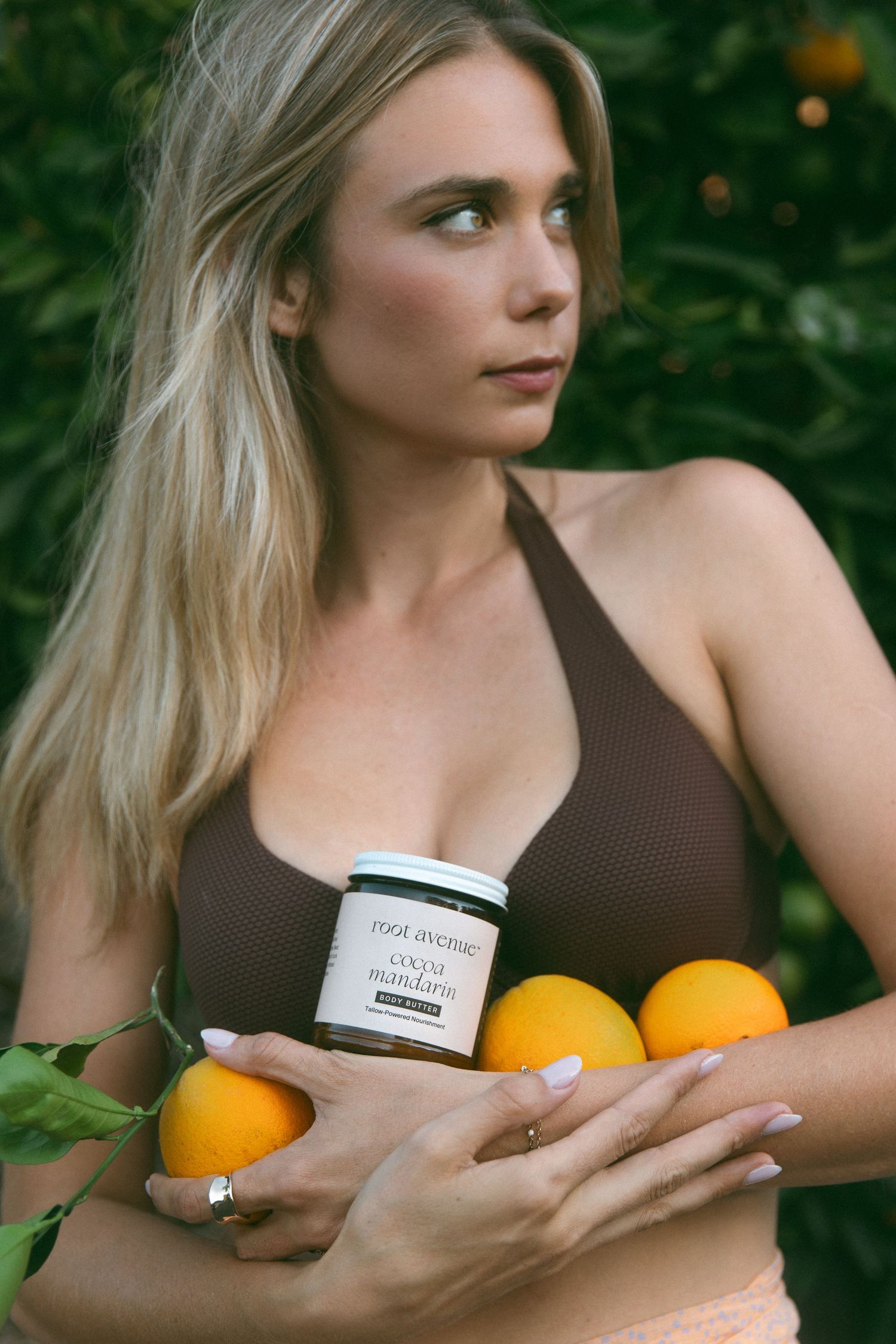 Product photography featuring skincare items and citrus fruits in a garden setting.
