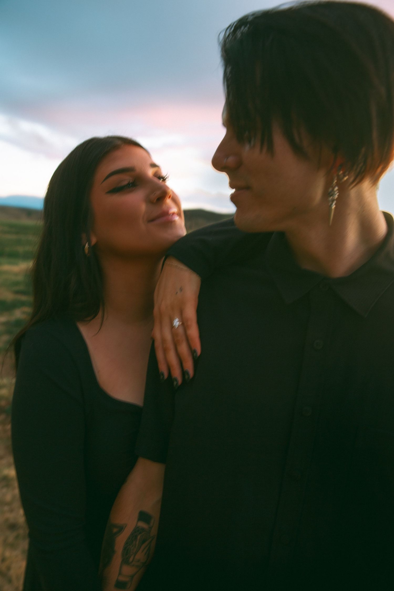 A couple shares an intimate moment during sunset in a rural setting.