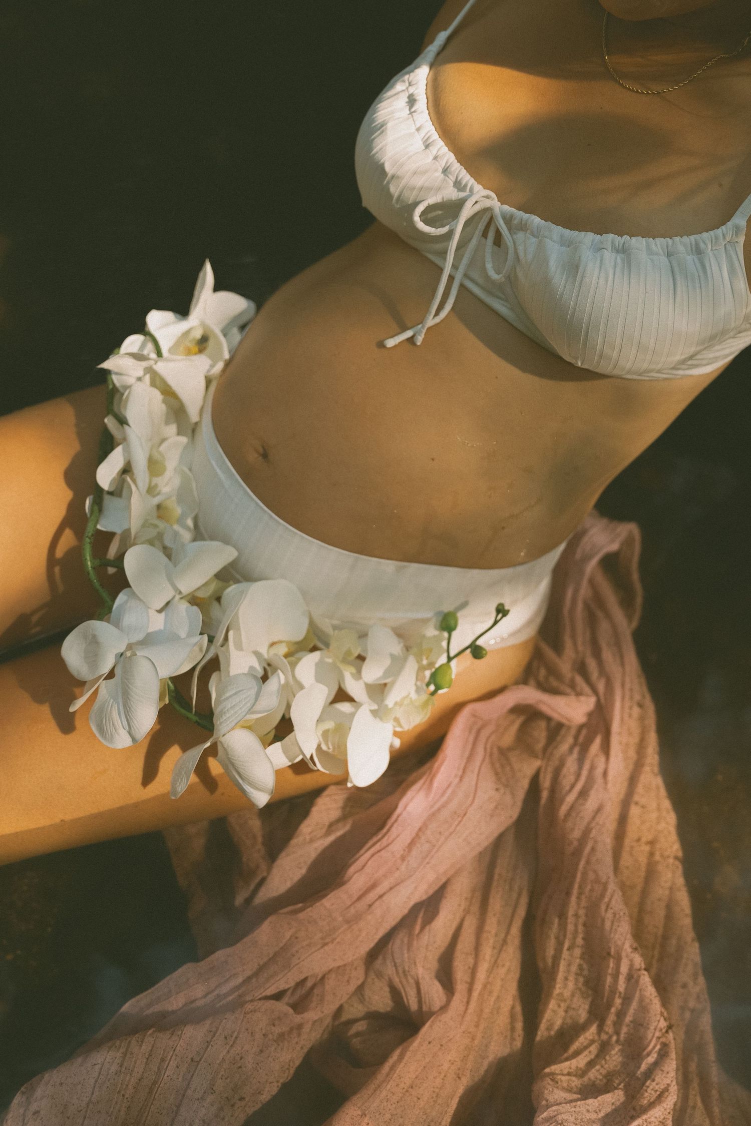 Close-up photo of white orchids adorning flowing fabric in warm lighting.
