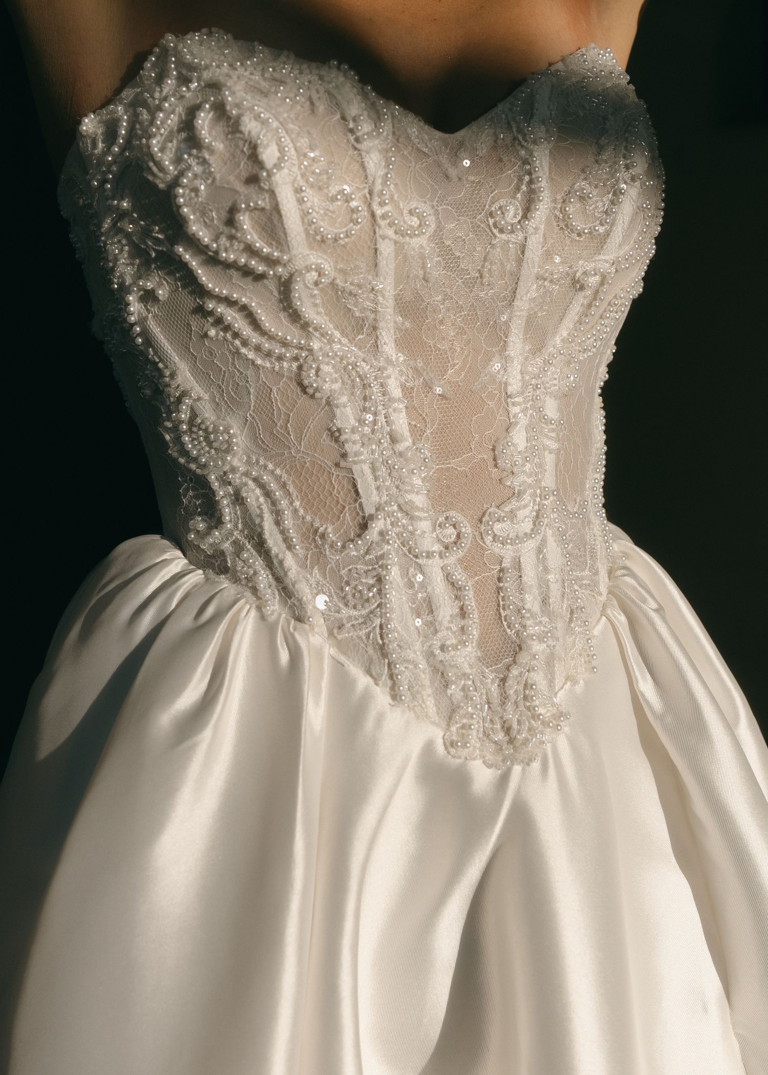 Elegant strapless wedding gown with intricate beaded lace corset bodice and full satin skirt in ivory white.