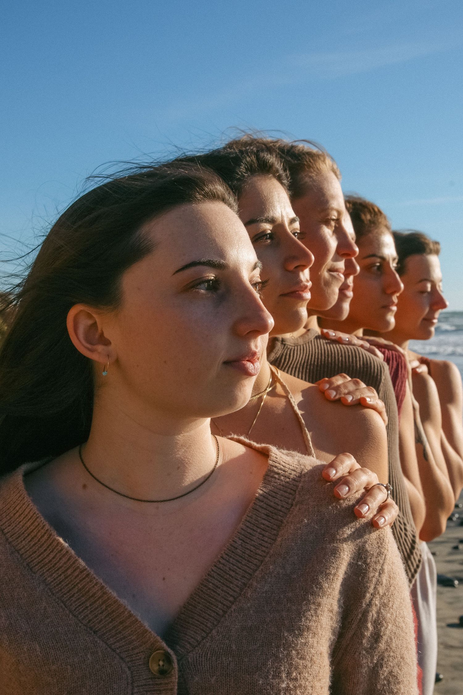 Group of people lined up outdoors looking to the side with soft lighting.