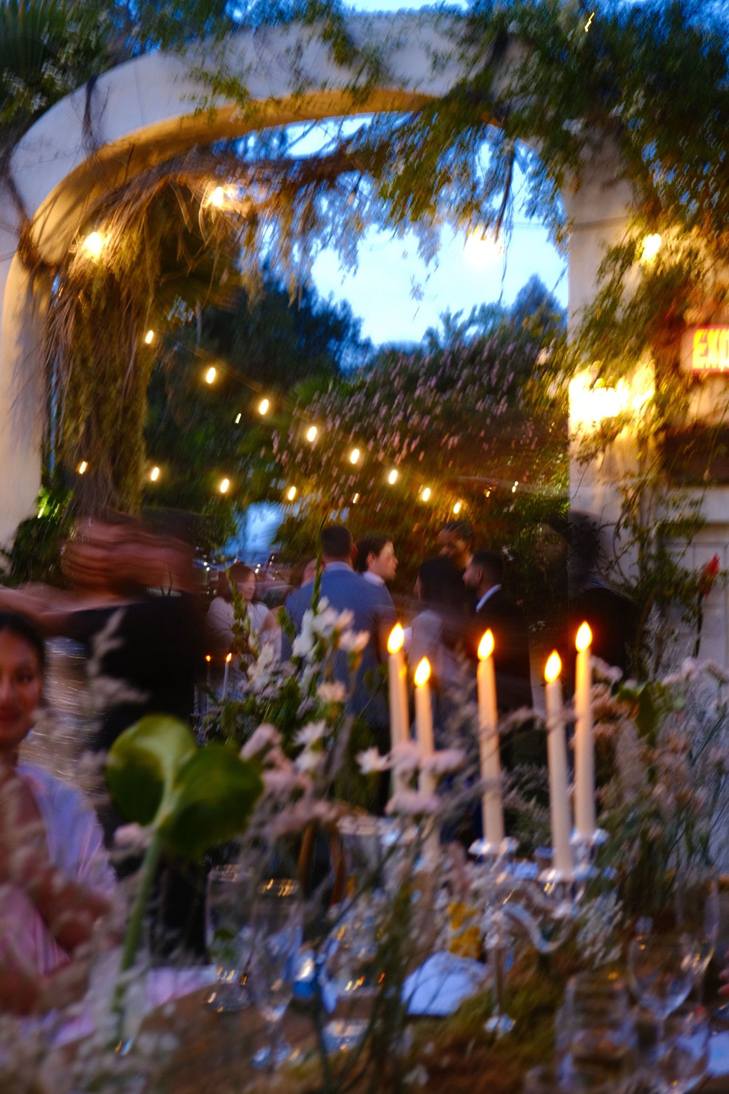 Outdoor evening wedding reception with twinkling lights and candles creating ambiance.