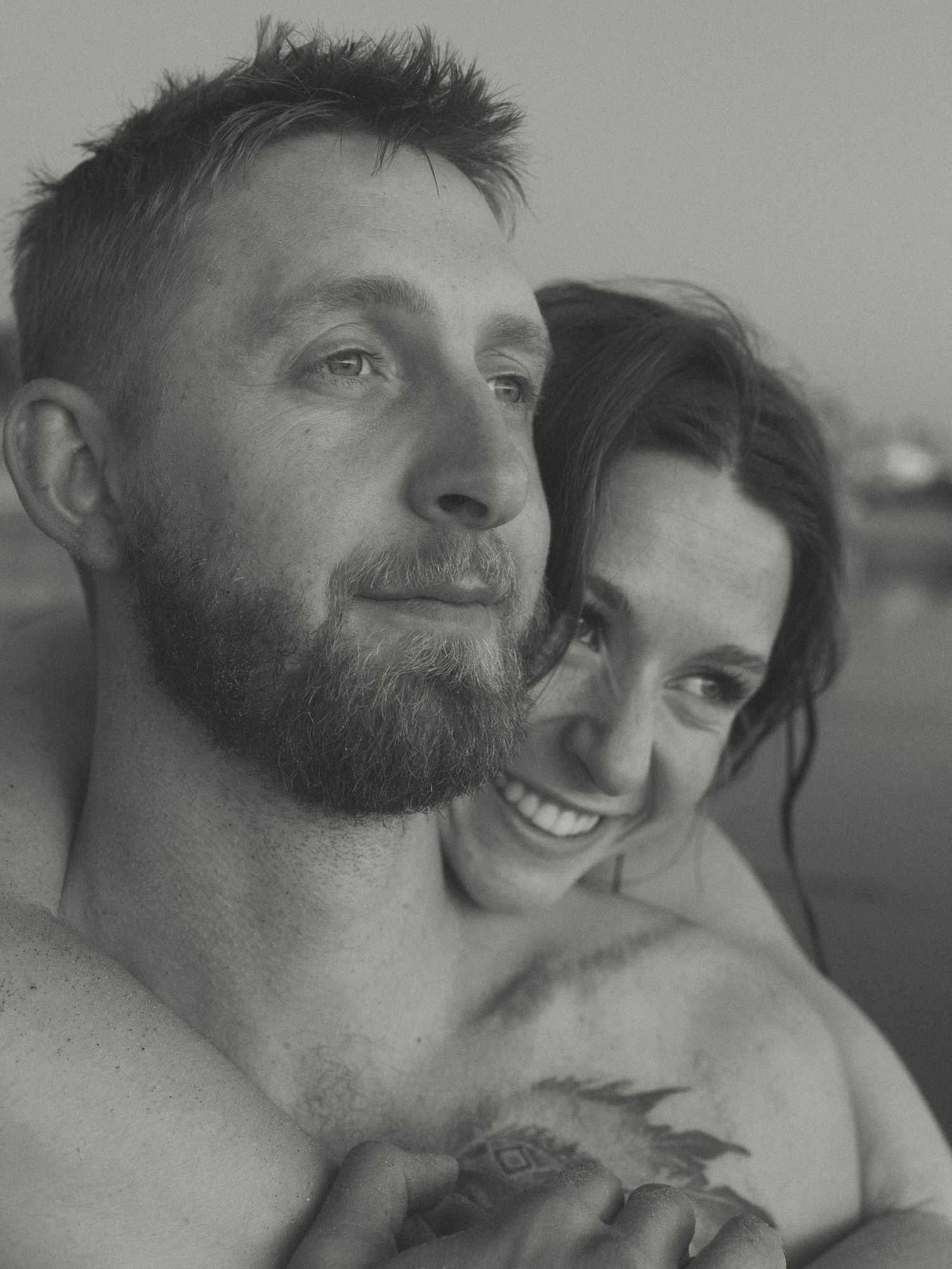 Black and white intimate portrait of a couple embracing and smiling together.