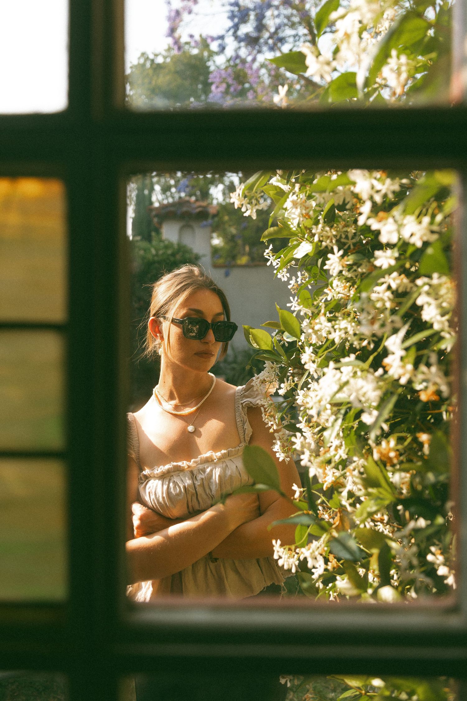 Sunlit figure through window panes with blooming tree branches in background.